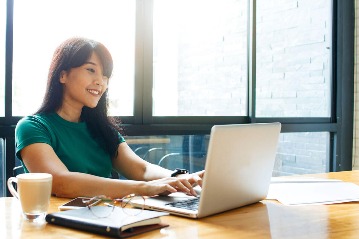 Female checking for unclaimed property on laptop, modern building