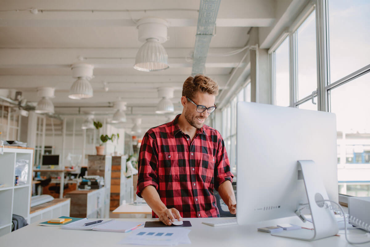 Male standing at modern computer, checking unclaimed property